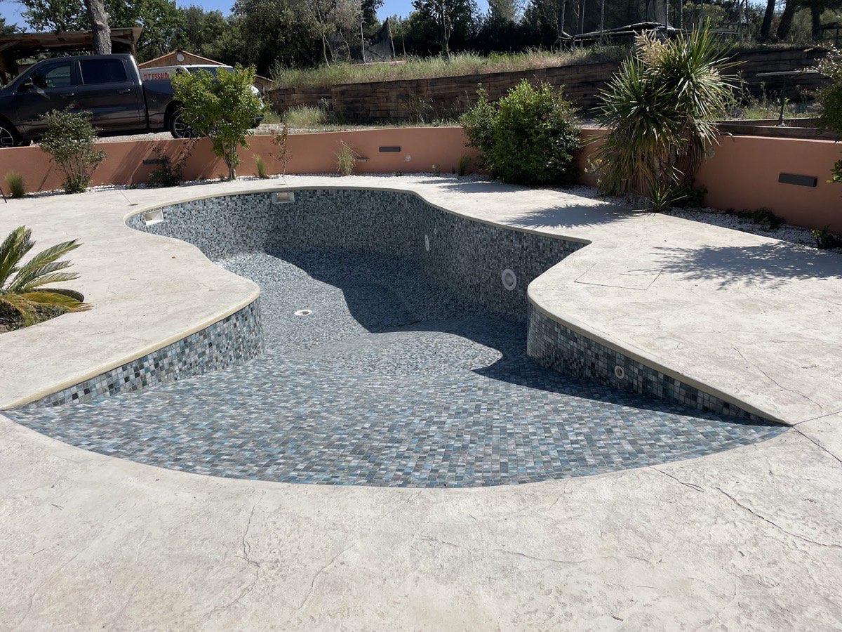 Piscine en mosaïque grise et bleue avec plage minérale